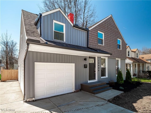view of front of property with driveway, a chimney, fence, an attached garage, and a shingled roof