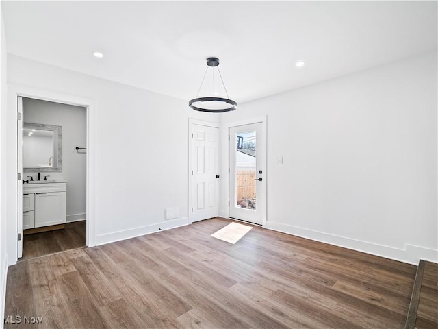 unfurnished bedroom with wood finished floors, access to exterior, baseboards, and a sink