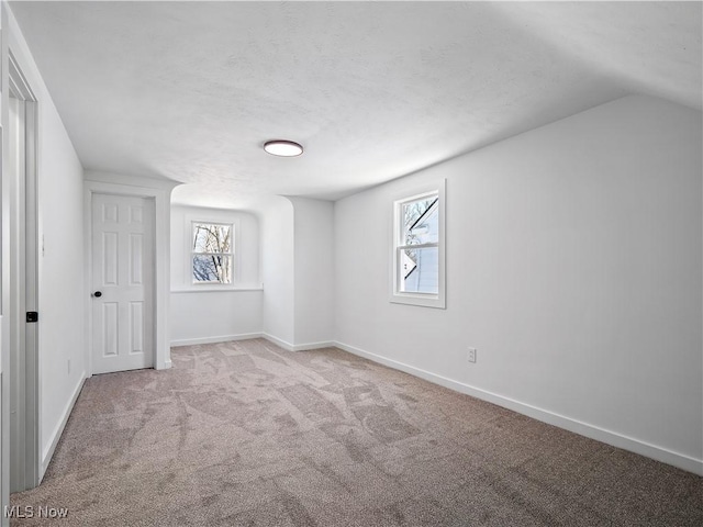 unfurnished bedroom featuring lofted ceiling, baseboards, carpet floors, and multiple windows