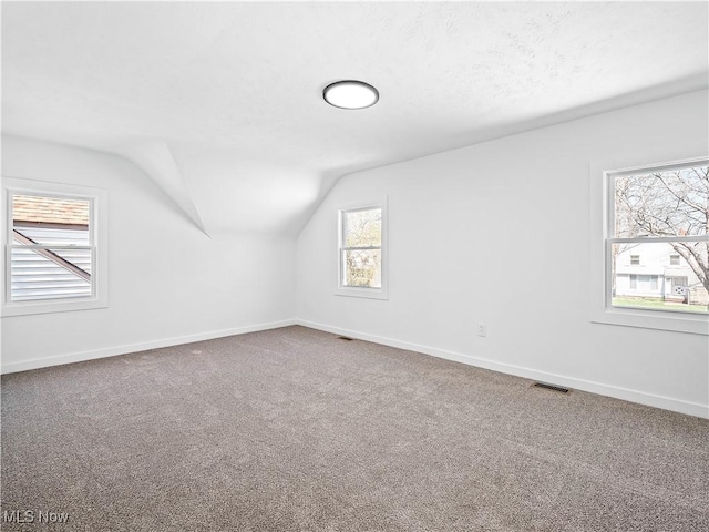 bonus room with vaulted ceiling, visible vents, baseboards, and carpet