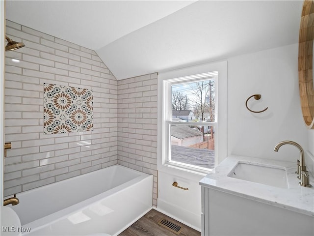 bathroom featuring vaulted ceiling, visible vents, a tub to relax in, wood finished floors, and vanity