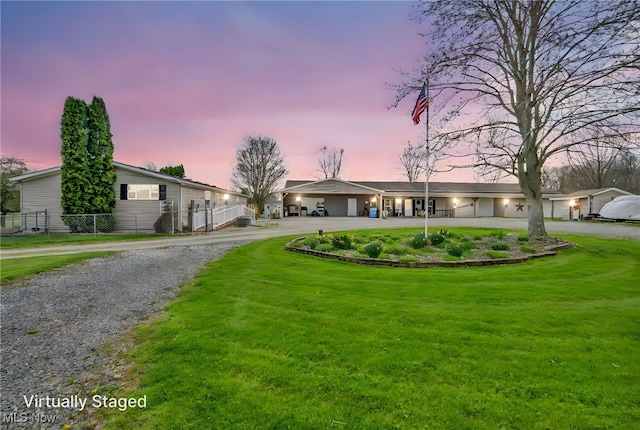 single story home featuring a lawn, fence, and curved driveway