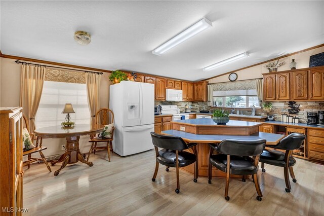 kitchen featuring decorative backsplash, vaulted ceiling, a center island, and white appliances