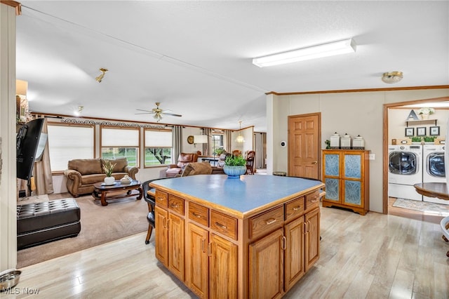 kitchen featuring open floor plan, independent washer and dryer, light wood-style floors, and a kitchen island