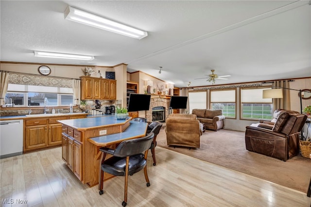 kitchen featuring open floor plan, lofted ceiling, dishwasher, a stone fireplace, and a breakfast bar area