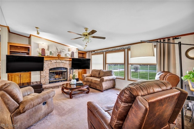 carpeted living room featuring a ceiling fan, lofted ceiling, ornamental molding, and a glass covered fireplace