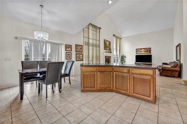 kitchen featuring light tile patterned flooring, open floor plan, a notable chandelier, high vaulted ceiling, and a fireplace