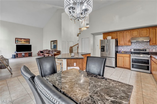 dining area featuring high vaulted ceiling, a chandelier, stairway, and light tile patterned floors