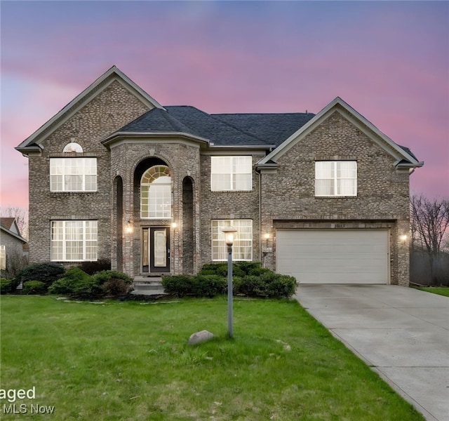 view of front of property featuring a garage, brick siding, a front lawn, and concrete driveway