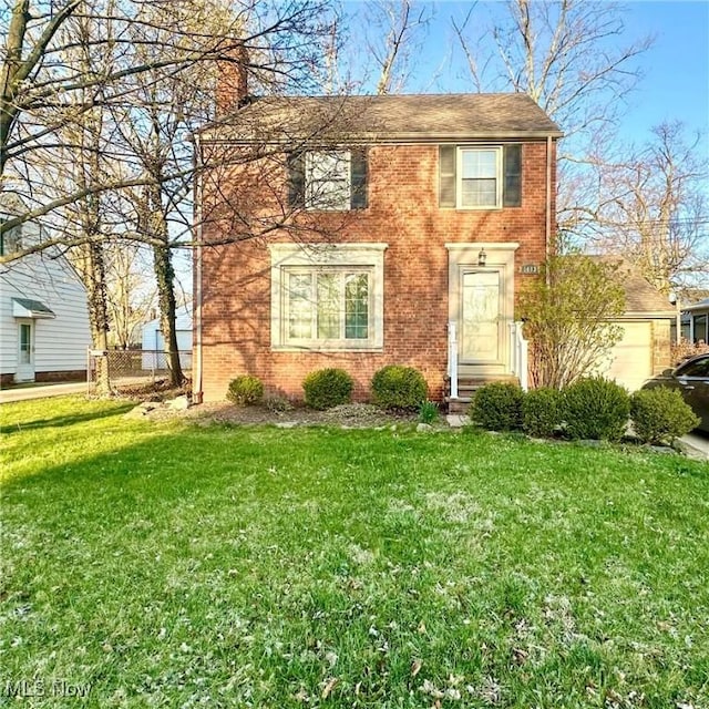 view of front of house with a front yard, a chimney, and brick siding