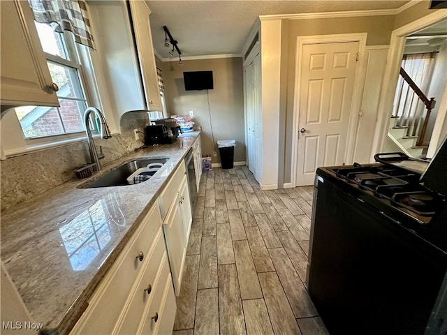 kitchen with light wood-style flooring, a sink, ornamental molding, gas stove, and backsplash
