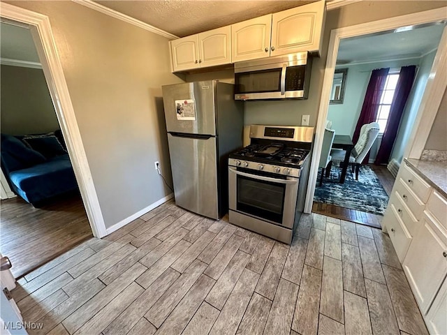 kitchen with a textured ceiling, white cabinetry, crown molding, light wood-style floors, and stainless steel appliances