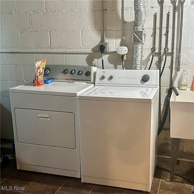 washroom with a sink, washer and clothes dryer, laundry area, and concrete block wall