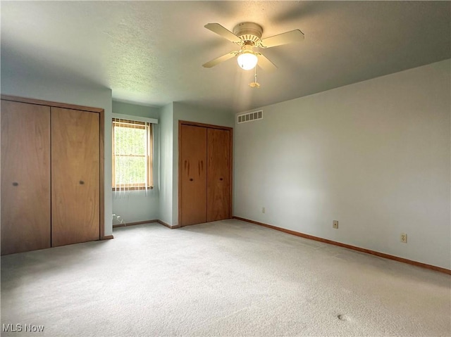 3799 Larchmont Ave NE, Bazetta, OH 44483 - unfurnished bedroom featuring two closets, baseboards, light colored carpet, and ceiling fan
