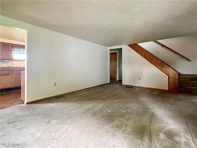 3799 Larchmont Ave NE, Bazetta, OH 44483 - unfurnished living room with baseboards, carpet flooring, stairs, and a textured ceiling