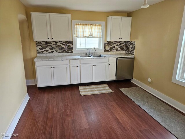 606 S 7th St, Cambridge, OH 43725 - kitchen featuring a sink, stainless steel dishwasher, baseboards, decorative backsplash, and white cabinetry