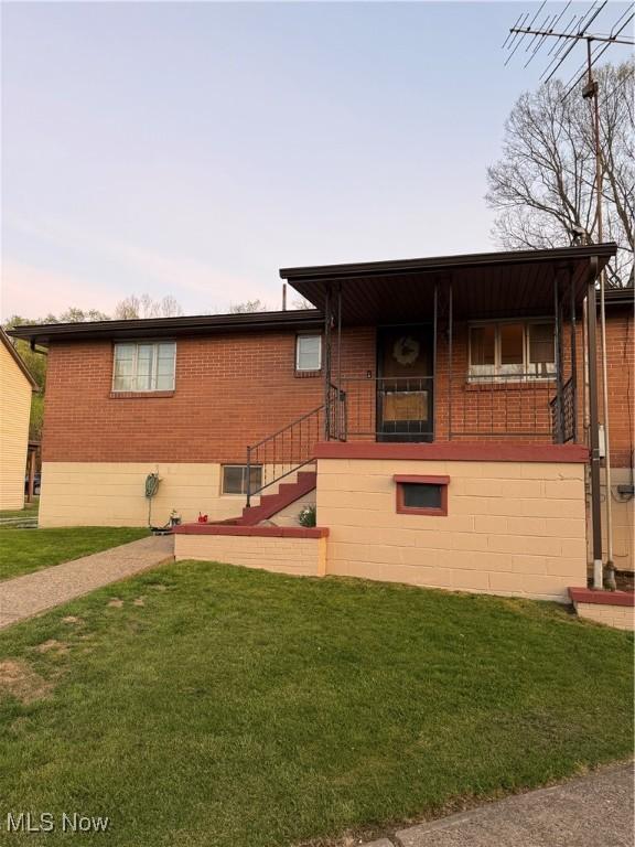 243 Hagan St, Adena, OH 43901 - ranch-style house featuring brick siding, a front lawn, and stairs