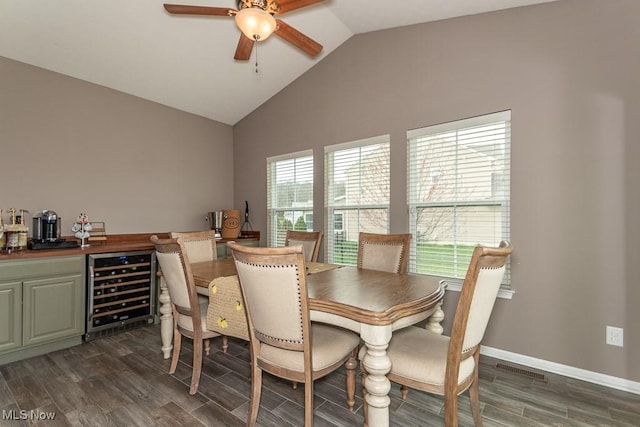 dining area with wine cooler, vaulted ceiling, a bar, a ceiling fan, and dark wood-type flooring