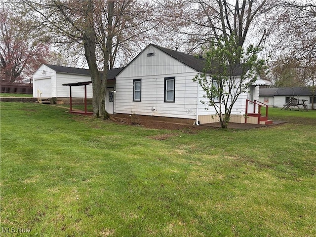 rear view of house featuring a yard and a detached garage