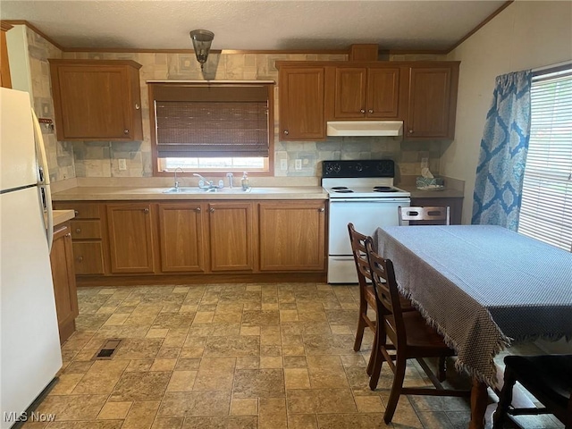kitchen featuring brown cabinetry, under cabinet range hood, tasteful backsplash, and white appliances