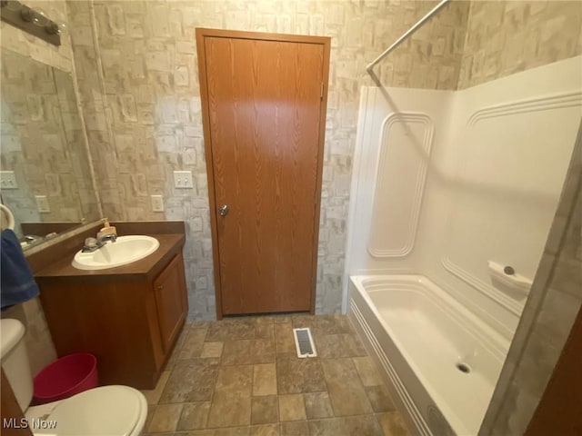 bathroom with stone finish floor, visible vents, shower / bath combination, vanity, and toilet