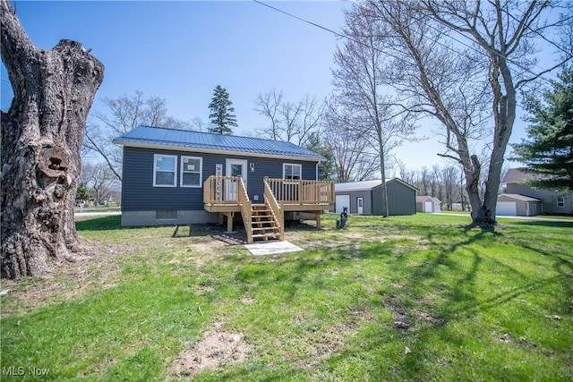 rear view of house featuring a wooden deck, a lawn, an outbuilding, and metal roof