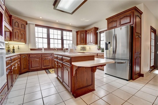 kitchen featuring a center island, a kitchen breakfast bar, stainless steel fridge, light countertops, and recessed lighting