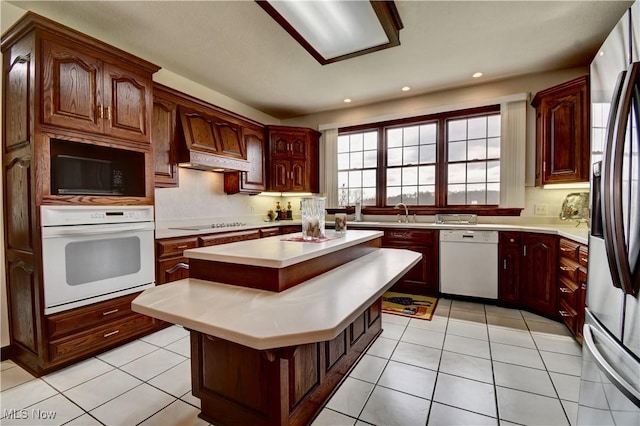 kitchen featuring a center island, light countertops, light tile patterned floors, and black appliances