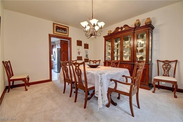 dining space with baseboards, a notable chandelier, and light colored carpet