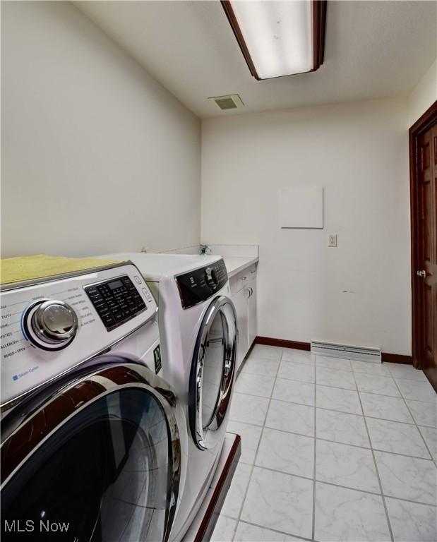 clothes washing area with cabinet space, visible vents, washing machine and clothes dryer, and baseboards