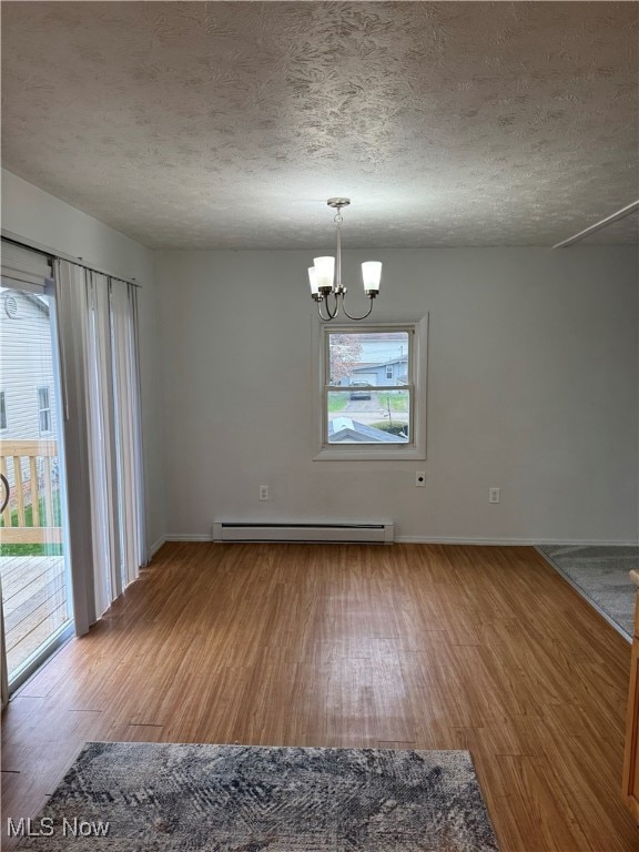 unfurnished dining area with wood finished floors, a textured ceiling, and a baseboard radiator