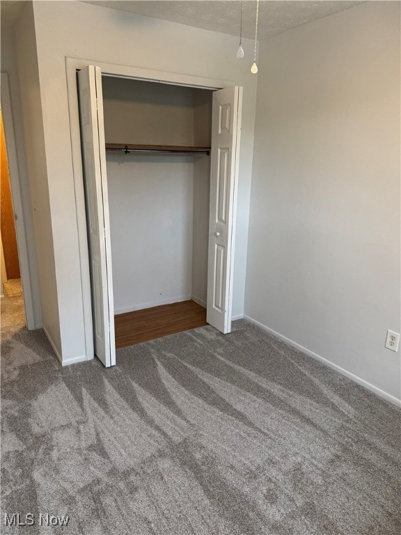 unfurnished bedroom featuring carpet floors, a closet, and baseboards