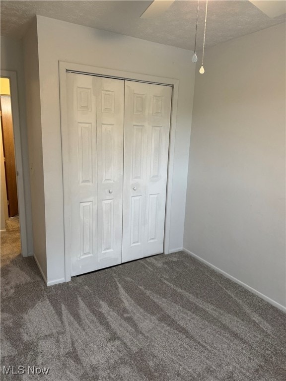 unfurnished bedroom with baseboards, carpet flooring, a textured ceiling, and a closet