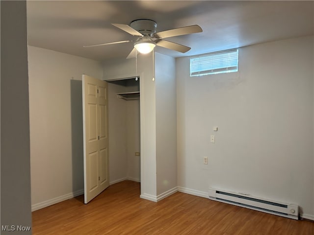 unfurnished bedroom with a baseboard radiator, baseboards, a ceiling fan, and light wood-style floors