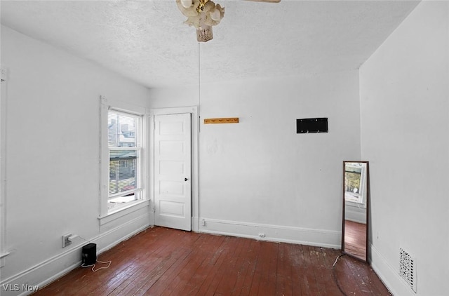 spare room featuring hardwood / wood-style floors, a ceiling fan, baseboards, and a textured ceiling