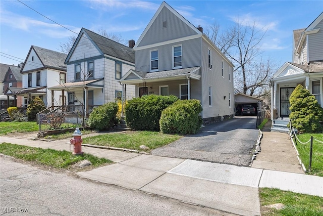 view of front of home featuring a chimney, a residential view, an outdoor structure, a porch, and a garage