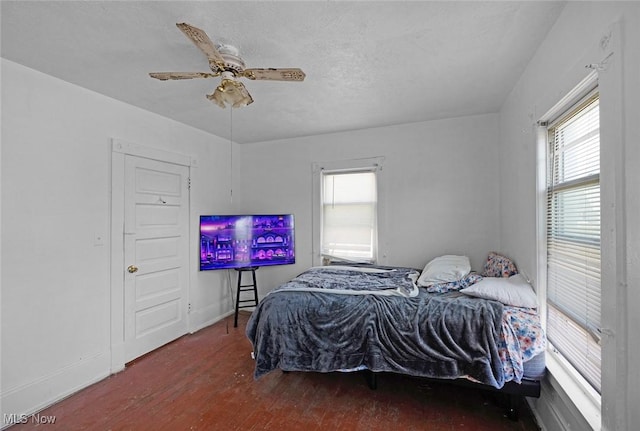 bedroom featuring wood finished floors, a ceiling fan, and baseboards