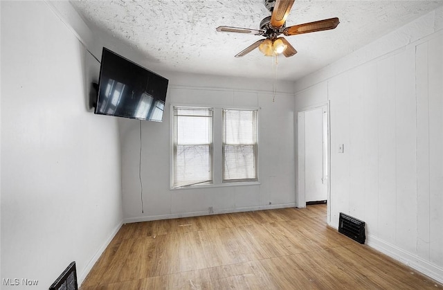 empty room featuring baseboards, visible vents, light wood-style floors, and ceiling fan