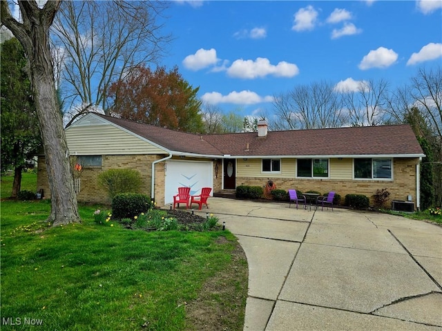 single story home with concrete driveway, central air condition unit, a front lawn, an attached garage, and brick siding