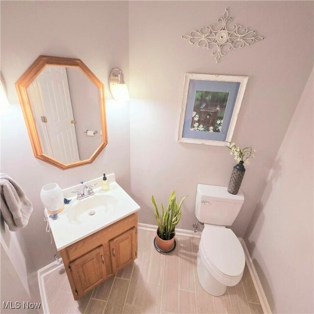 bathroom featuring toilet, vanity, and baseboards