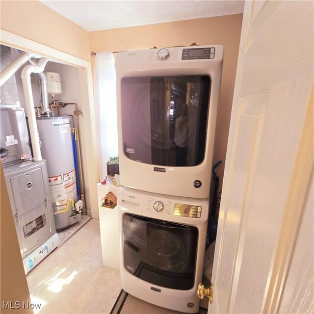 washroom featuring laundry area, stacked washer and dryer, gas water heater, and light tile patterned floors