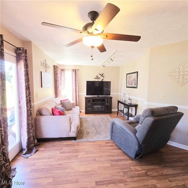 living room with rail lighting, a healthy amount of sunlight, wood finished floors, and ceiling fan