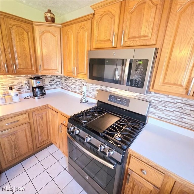 kitchen featuring light countertops, tasteful backsplash, appliances with stainless steel finishes, and light tile patterned flooring