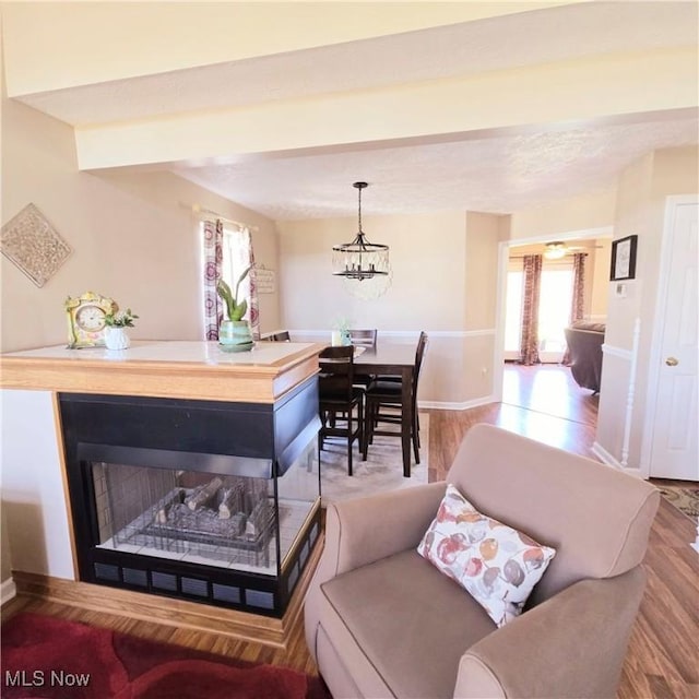 living room featuring baseboards, wood finished floors, a wealth of natural light, and a notable chandelier