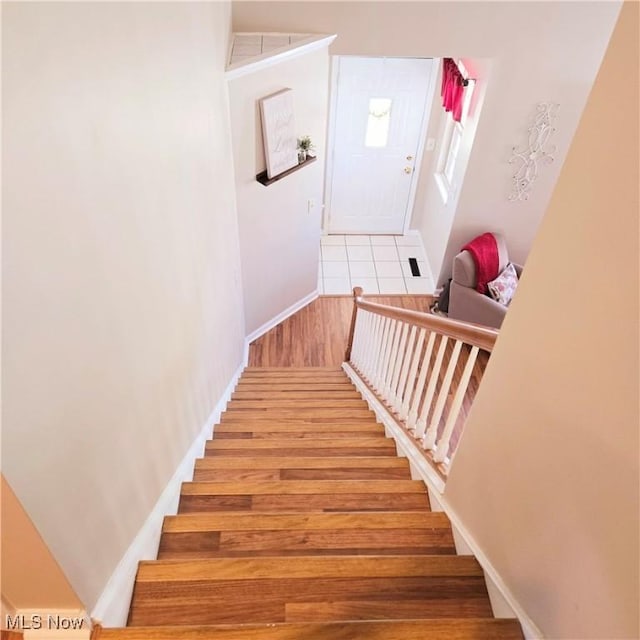 staircase featuring wood finished floors and baseboards