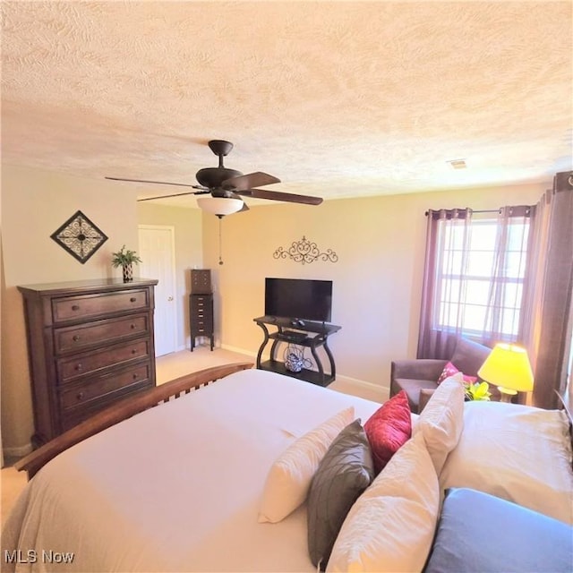 bedroom with baseboards, a ceiling fan, and a textured ceiling