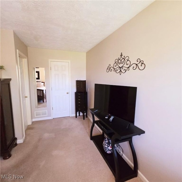 corridor featuring carpet, baseboards, and a textured ceiling