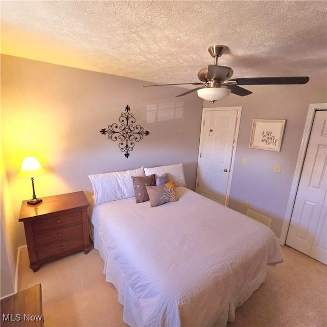 bedroom with ceiling fan, light carpet, a textured ceiling, and a closet