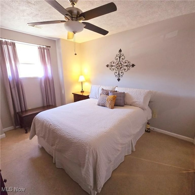 bedroom featuring ceiling fan, baseboards, a textured ceiling, and light carpet