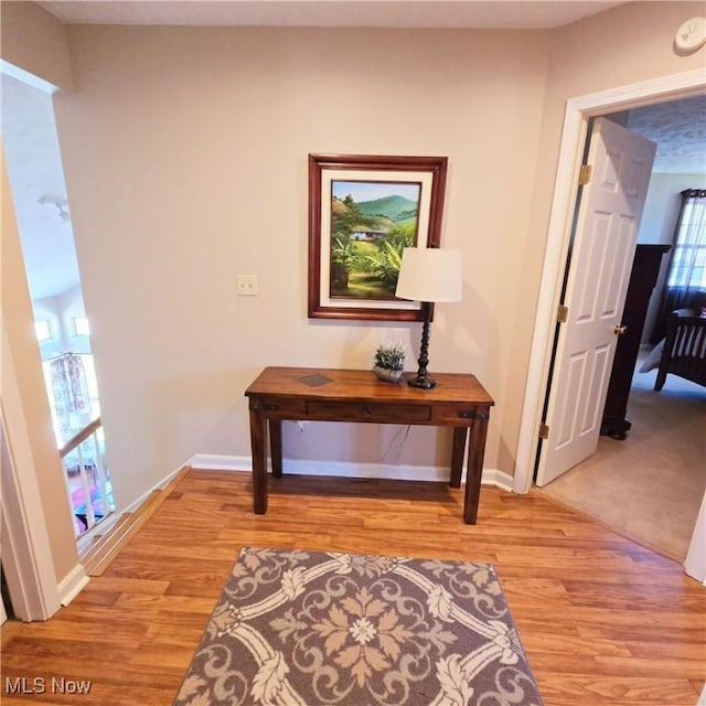 hallway with light wood-type flooring and baseboards